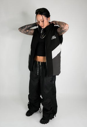 Model wearing the Take A Gamble Vest with black and gray color blocks, paired with black pants and a crop top, showcasing a modern streetwear look.